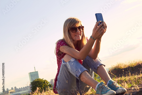 Young woman using modern smartphone outdoors. photo