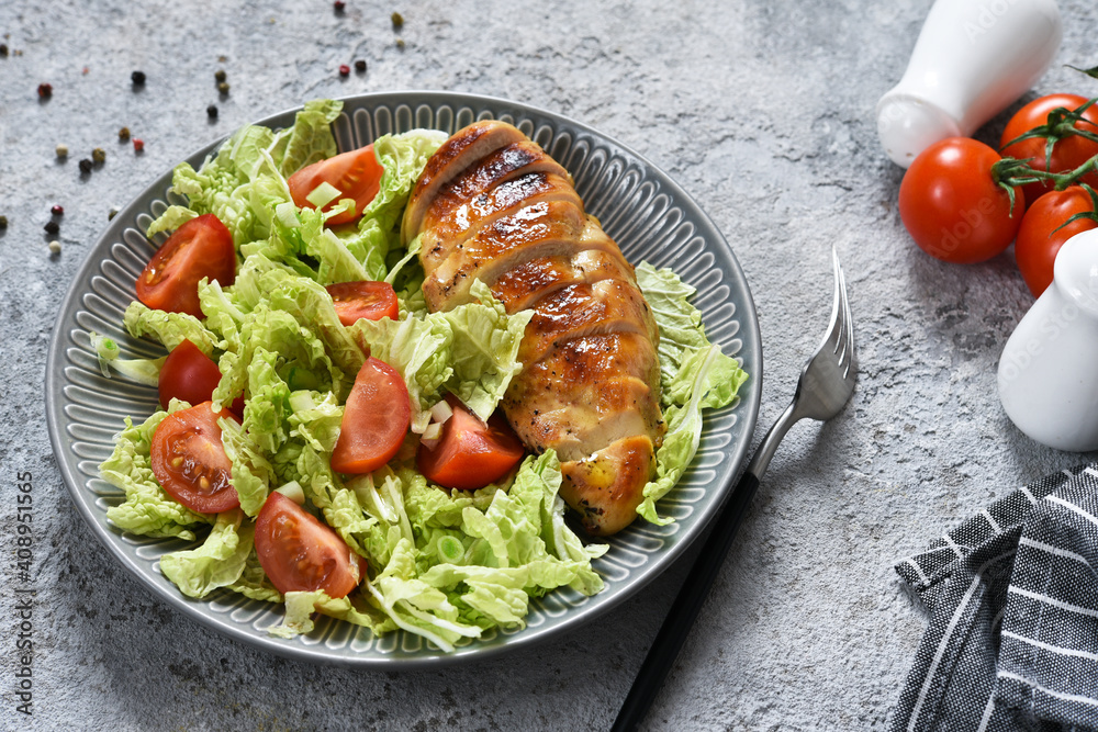Baked chicken breast and salad with tomatoes on a concrete background. Healthy food, keto diet, paleo diet. Top view with copy space.