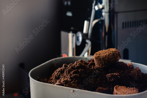 Used coffee grounds from espresso machine. Recycling compost container filled with used coffee waste. Coffee machine cleaning.