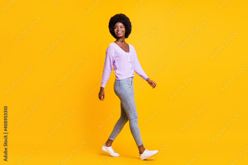 Full size profile photo of positive dark skin person walking look empty space isolated on yellow color background