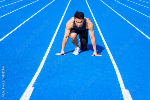 Male athlete on race track is ready to run