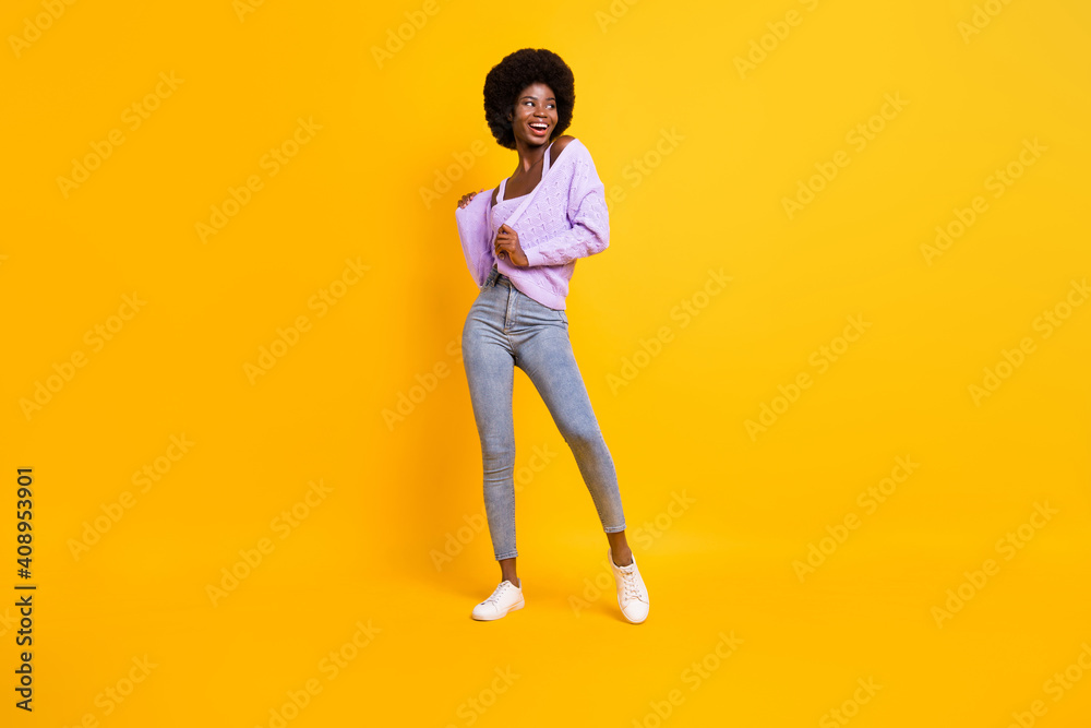 Full length photo of adorable carefree dark skin lady look empty space isolated on yellow color background Full length photo of adorable carefree dark skin lady look empty space isolated on yellow color background