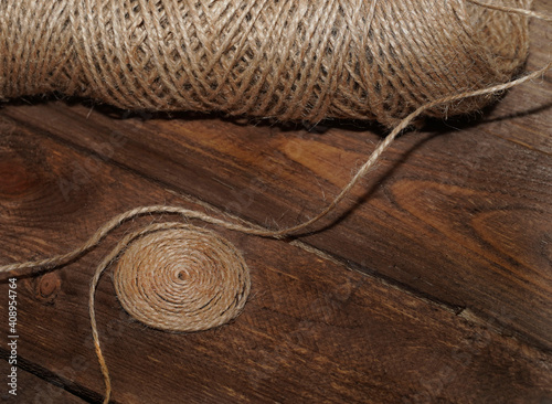 Skein of jute rope and circle made of jute on an old wooden background. Closeup. Vintage, retro, home decor, country concept.