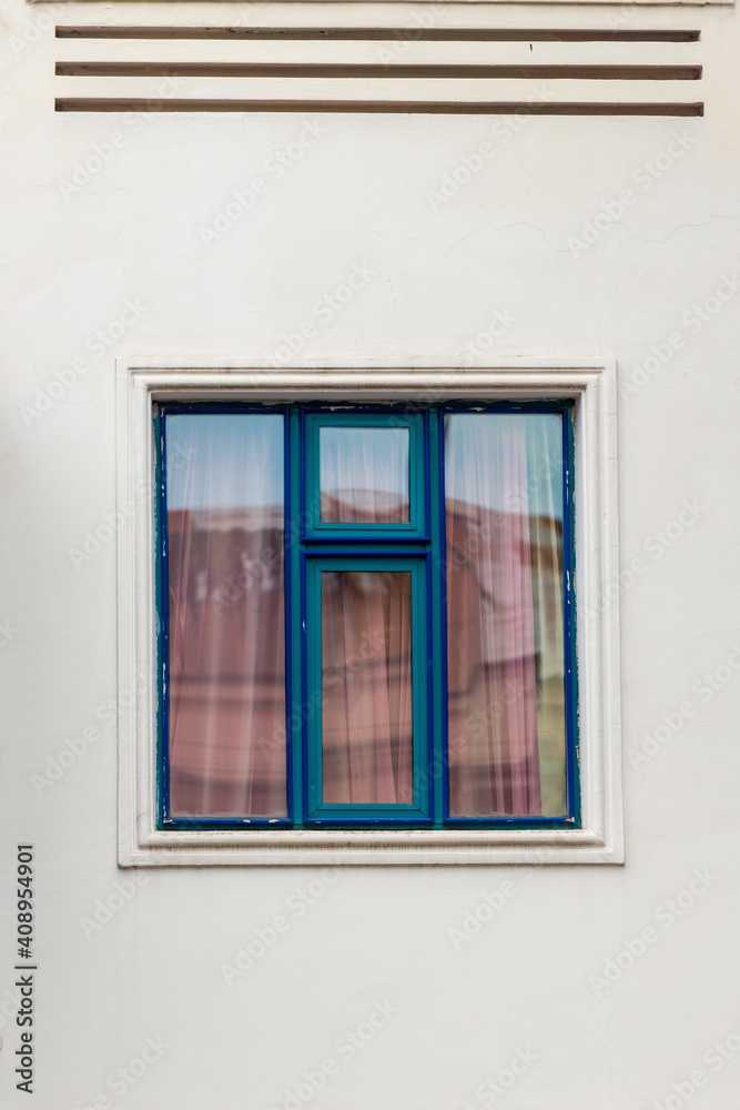 White wall and blue window in the center of the frame, architecture detail