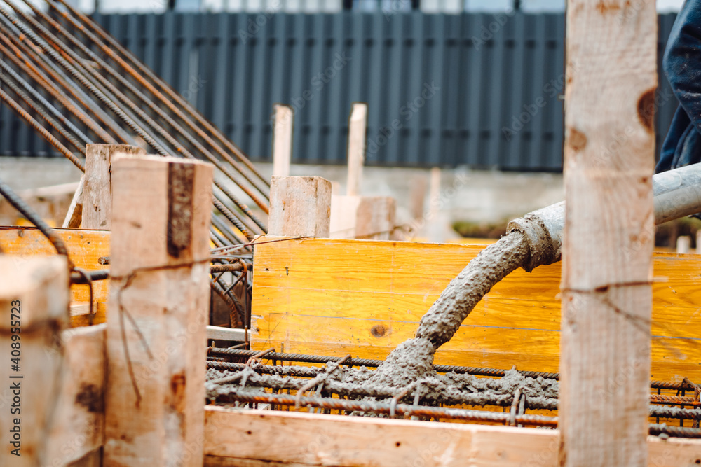 Fototapeta premium caucasian workers pouring concrete with concrete pump. Details of construction site and close up details of worker workwear