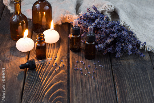 bottles of aromatic oil, candles and lavender flowers