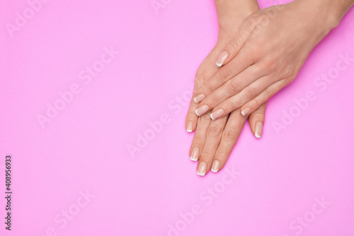 Beautiful Female Hands with French manicure over colorful paper background
