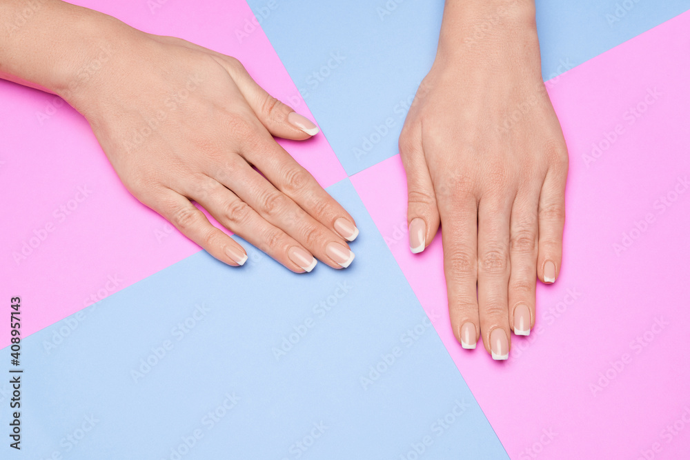 Naklejka premium Beautiful Female Hands with French manicure over colorful paper background