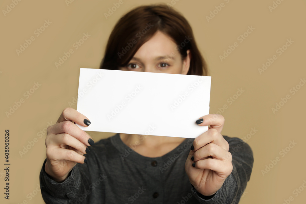 Portrait of young woman holds blank white paper tag.
Portrait of young woman holds blank white paper tag.