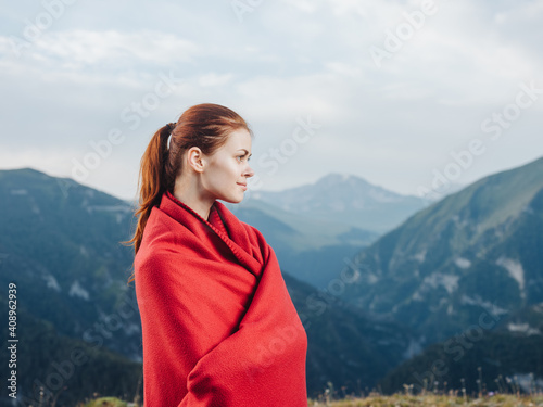 woman traveler with a red plaid on her shoulders in the mountains