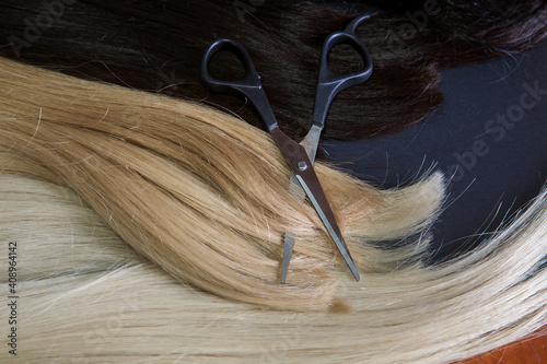 hair extensions and scissors on a dark background. Hair Care Concept. 