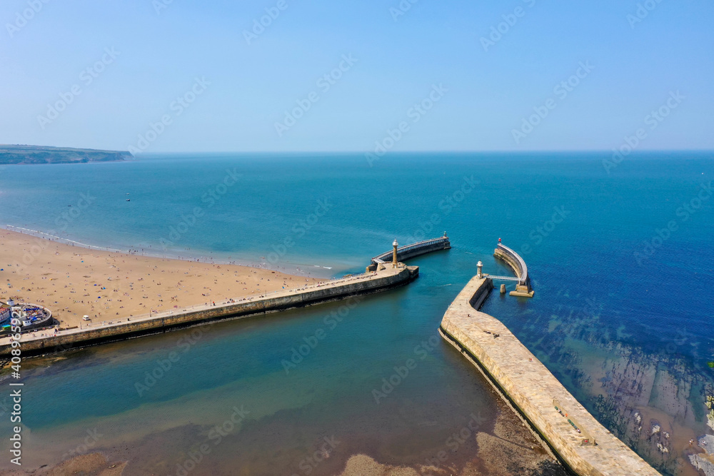 Aerial photo of the beautiful town of Whitby in the UK in North Yorkshire in the UK showing the pier and light house Aerial photo of the beautiful town of Whitby in the UK in North Yorkshire in the UK showing the pier and light house