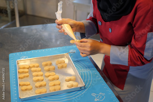 Yogyakarta, Indonesia, June 29, 2020. A cake maker is applying topping cream on top of a cookie, just before the oven cooking process.