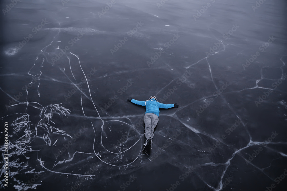 a man in ice skates lies on the transparent ice of the lake, view from above, aerial photography