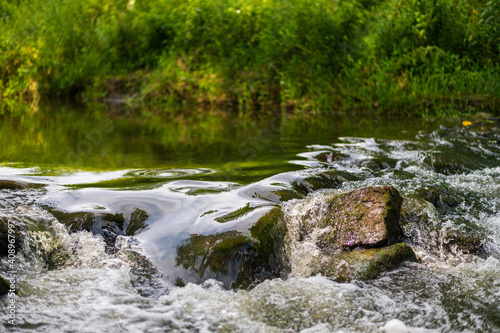 River flow over rocks in summer day. Waves of the river flow. Relaxing nature landscape scenics
