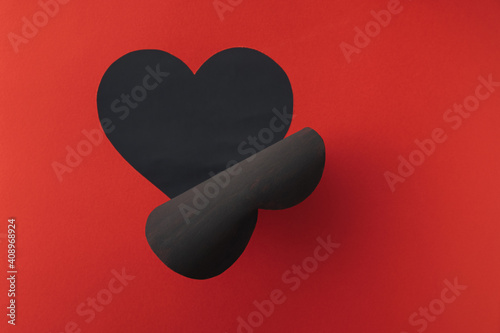 Love concept art with cutout peeling away to reveal black heart on red background