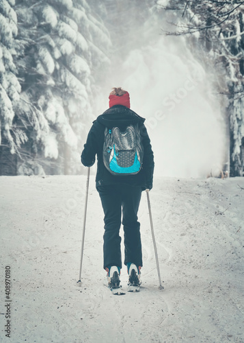 Back view of a woman skier with a backpack on a ski slope in Carpathian Mountains Romania. photo