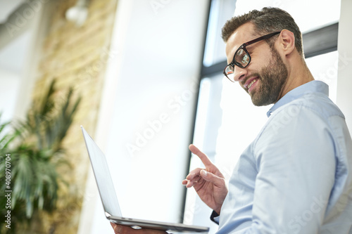 Cheerful office employee with modern gadget at work