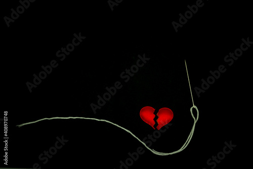 Obraz na płótnie Healing broken heart concept, red heart is sewn with  white thread with needle o