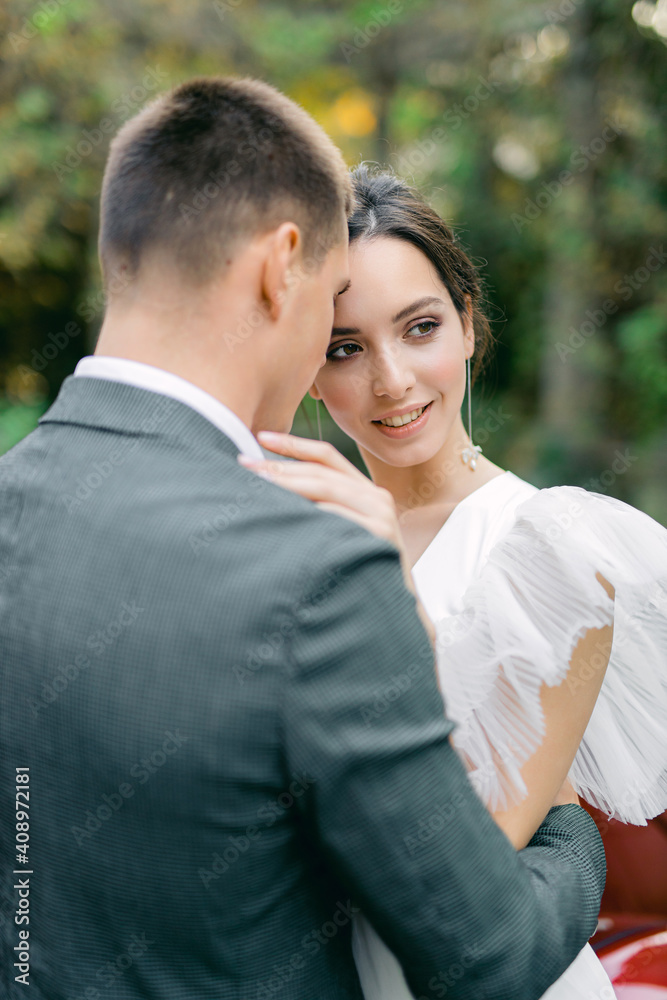 Amazing smiling wedding couple. Pretty bride in fashion white wedding dress and stylish groom in gray tuxedo. Amazing smiling wedding couple. Pretty bride in fashion white wedding dress and stylish groom in gray tuxedo.
