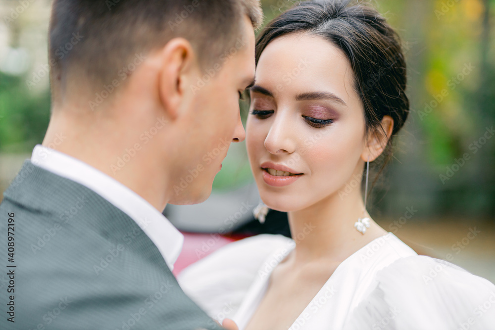 Amazing smiling wedding couple. Pretty bride in fashion white wedding dress and stylish groom in gray tuxedo Amazing smiling wedding couple. Pretty bride in fashion white wedding dress and stylish groom in gray tuxedo