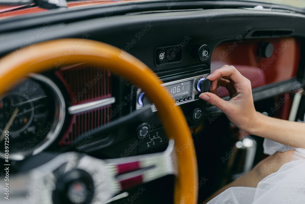 A man tunes the radio in a retro car.