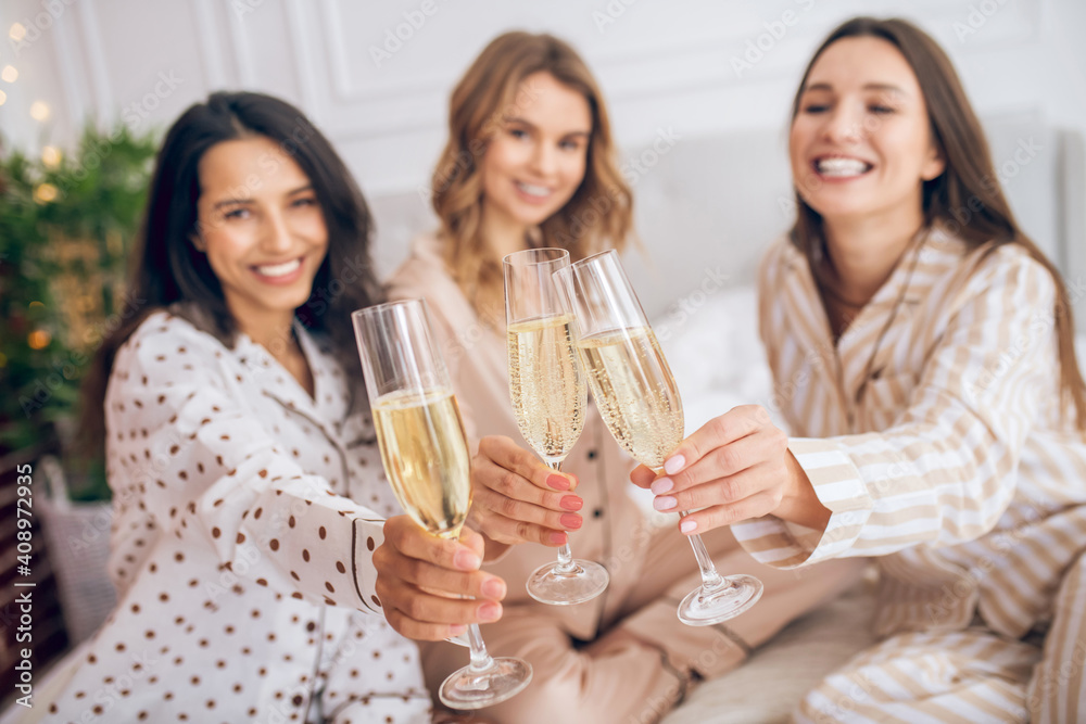 Three pretty girls having pajama party and drinking champagne Three pretty girls having pajama party and drinking champagne