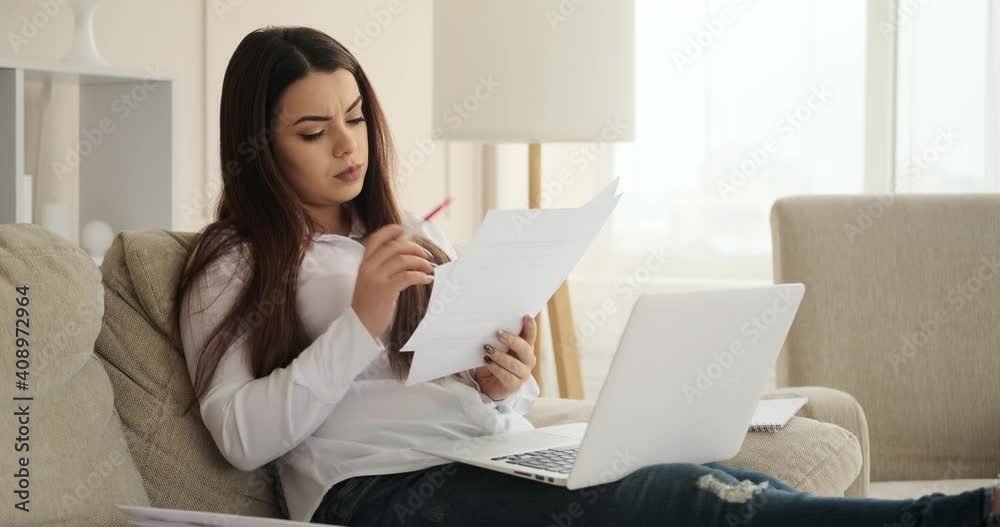 Thoughtful woman analyzing documents while working at home Thoughtful woman analyzing documents while working at home