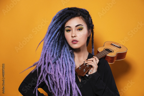 Valokuva beautiful young woman with lilac dreadlocks and multi-colored makeup stands on a