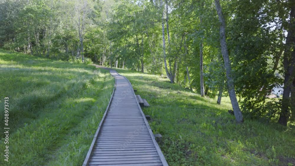 Wooden path along the banks of the Gauja river in the national park of Latvia. Sunny summer day off in nature. People rest and have picnics on a warm day Wooden path along the banks of the Gauja river in the national park of Latvia. Sunny summer day off in nature. People rest and have picnics on a warm day