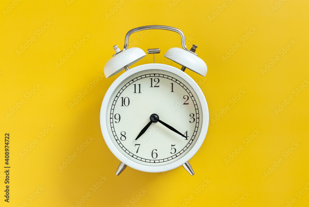 white circle retro classic analog alarm clock with clock needle isolated on yellow empty background with copy space. time management concept.