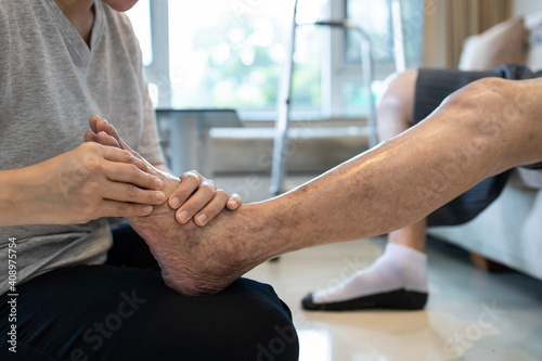 Foot massage physical therapy to relieve muscle spasms,massage the tired muscles of senior woman,feet numb from diabetes,old elderly with diabetic numbness of the toes,problems of peripheral nerves photo