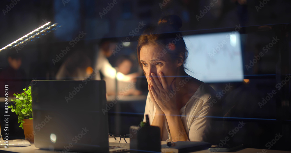 Stressed businesswoman with computer working at night office