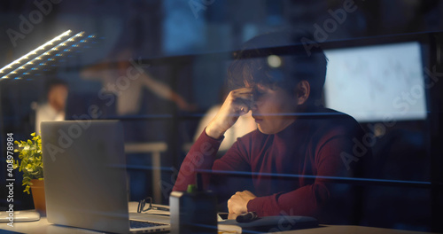 Photos Young businessman having headache working overtime on laptop in office late nigh