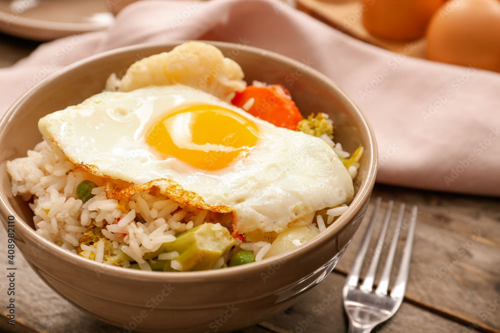 Bowl with tasty egg, vegetables and rice on wooden background Bowl with tasty egg, vegetables and rice on wooden background