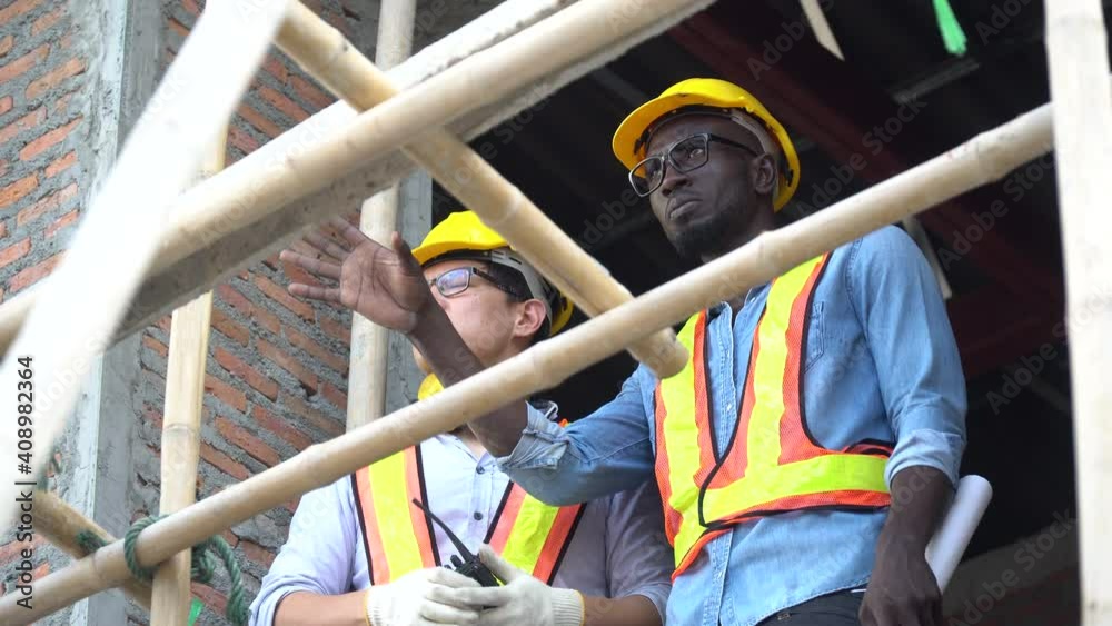 asian foreman and african american architect discuss with blueprint outdoors on construction site at village . contractor worker Inspection with builder . Engineer and foreman . quality control asian foreman and african american architect discuss with blueprint outdoors on construction site at village . contractor worker Inspection with builder . Engineer and foreman . quality control