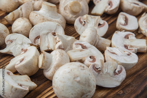 A handful of whole and sliced champignons lies on a dark wooden board
