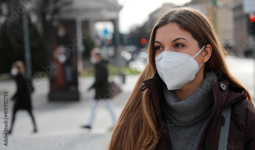 Social distancing respected. Portrait of young woman wearing FFP2 KN95 face mask in winter clothes outdoors.