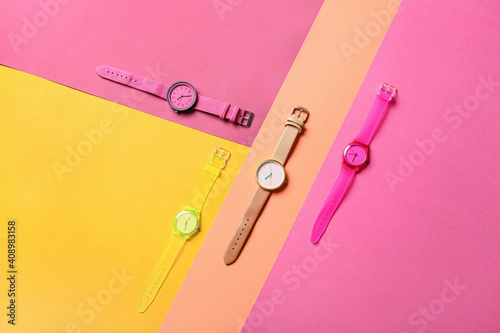 Stylish wrist watches on colorful background