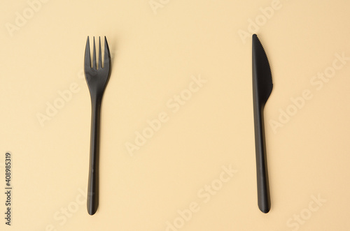 disposable black plastic fork and knife on a brown background  close up  set  copy space