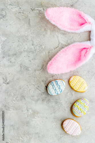 Top view of Easter bunny ears with eggs cookies, space for text