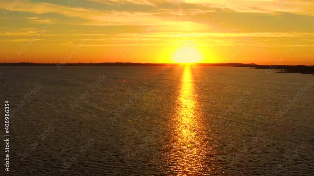 Aerial view, Kitesurfers swim at high speed in the open sea at sunset. Drone shot at three athletes on boards floating above the water surface. Poland Hel