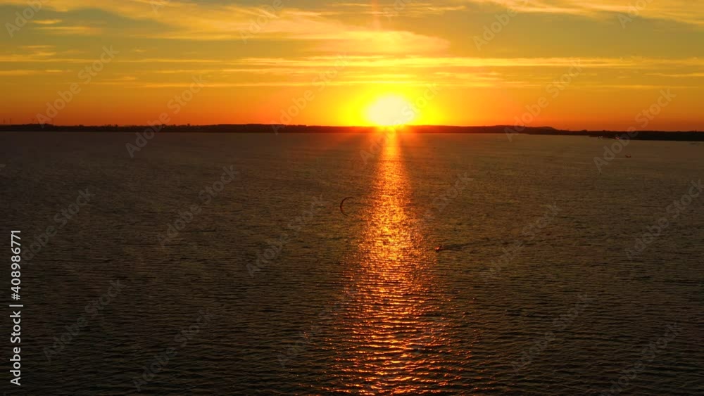 Aerial view, Kitesurfers swim at high speed in the open sea at sunset. Drone shot at three athletes on boards floating above the water surface. Poland Hel