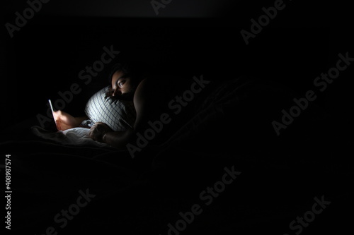 Young man looking at phone in bed