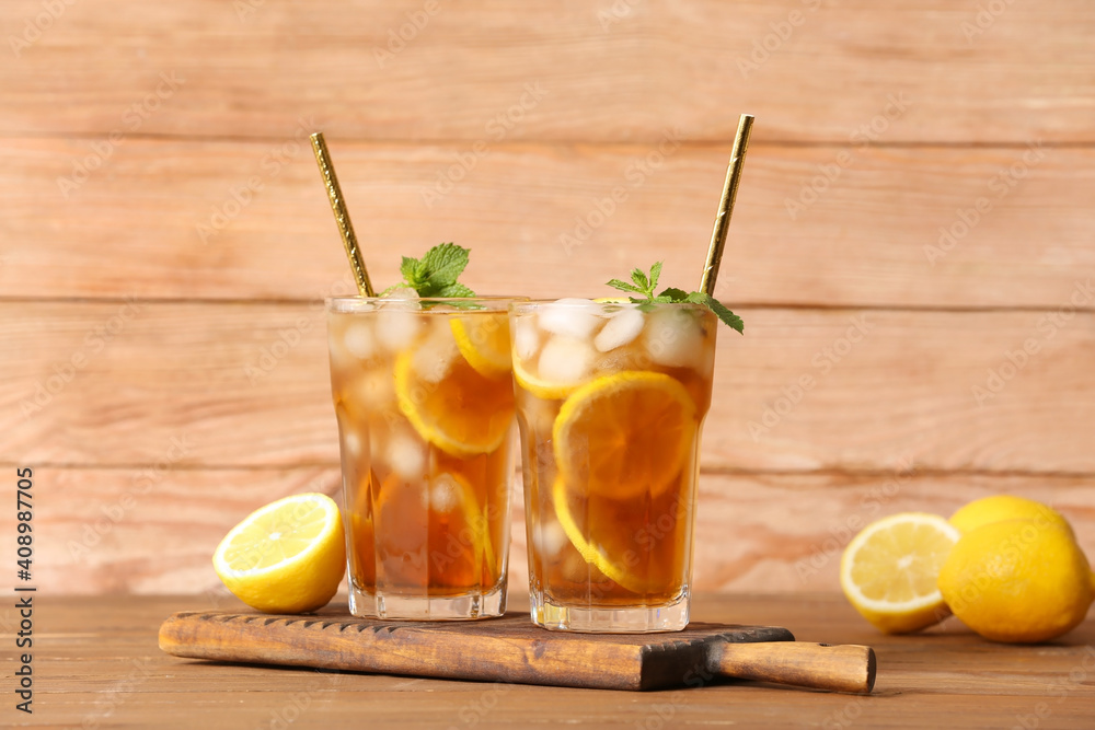 Fototapeta premium Glasses of cold black tea with lemon on wooden background