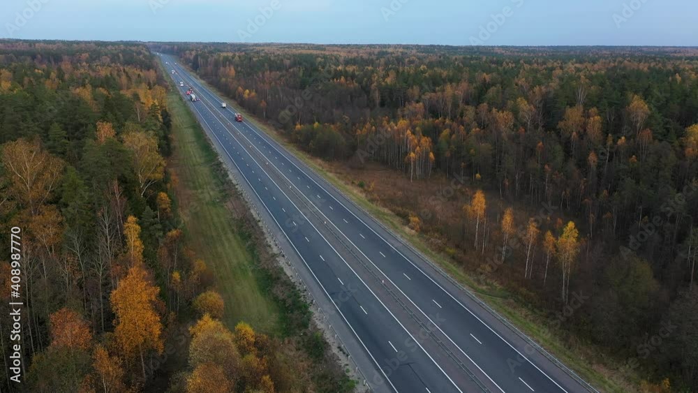 Aerial view of road between autumn forests in countryside.