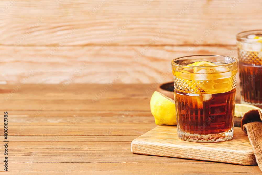 Glass of cold black tea with lemon on wooden background Glass of cold black tea with lemon on wooden background