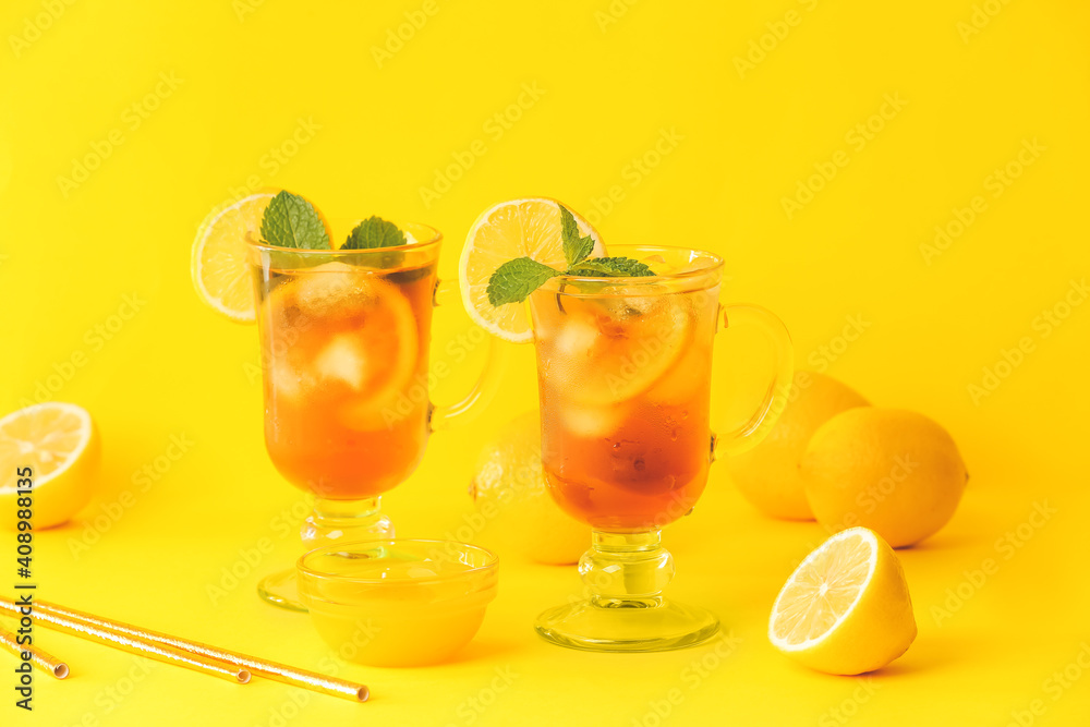 Fototapeta premium Cups of cold black tea with lemon on color background