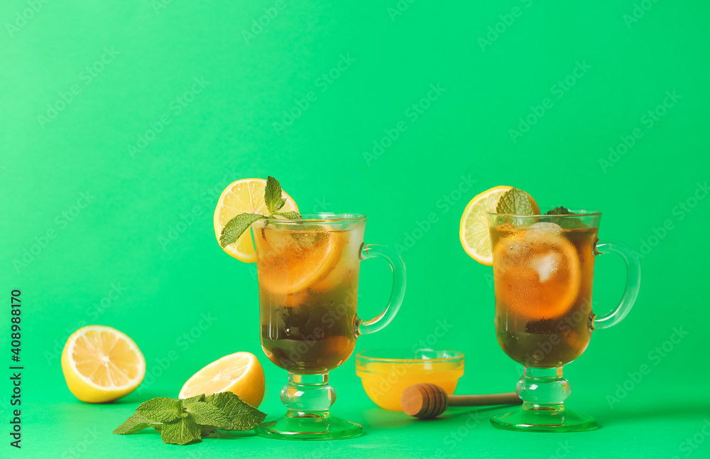 Fototapeta premium Cups of cold black tea with lemon on color background