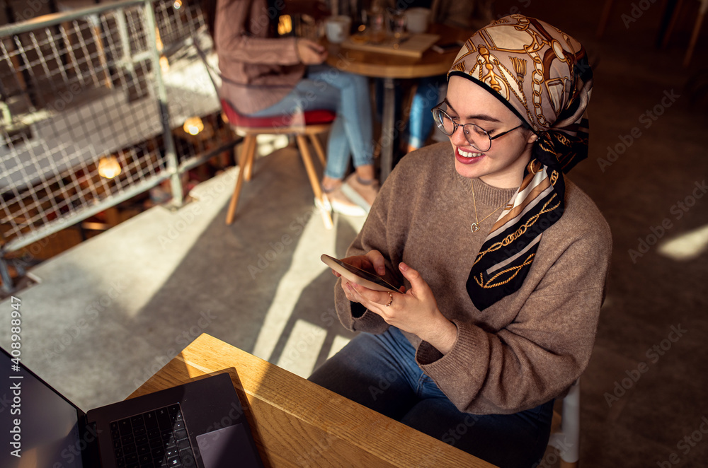 Portrait of young middle eastern woman using smartphone in coffee shop.